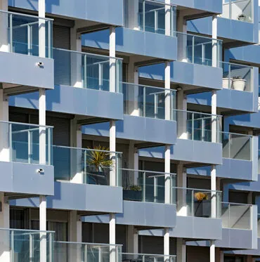 immeuble en bord de mer avec des garde-corps vitrés, vitrage clair, modèle prêt à poser avec doubles poteaux intermédiaires et habillage de la dalle avec un bandeau en aluminium
