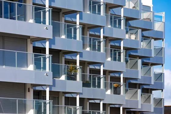 immeuble en bord de mer avec des garde-corps vitrés, vitrage clair, modèle prêt à poser avec doubles poteaux intermédiaires et habillage de la dalle avec un bandeau en aluminium